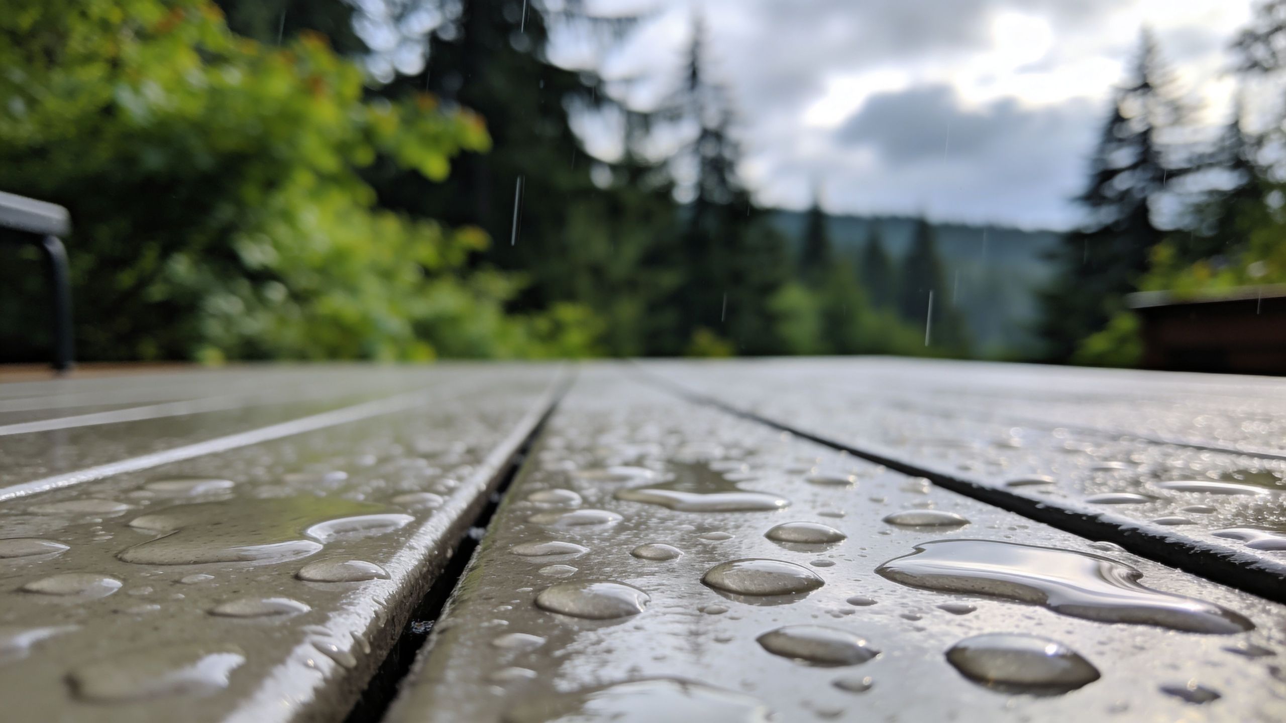 Raindrops resting on a smooth, modern grey composite deck after a light summer rain shower outdoors.